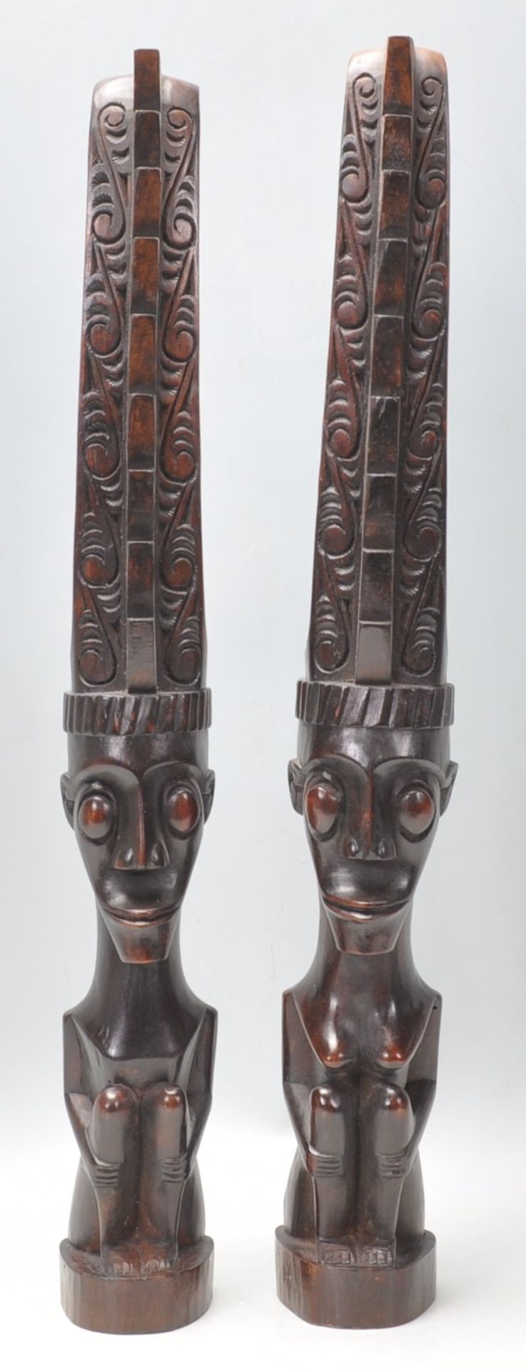 A pair of 20th Century carved dark wood African tribal figurines in the form of stylised crouched