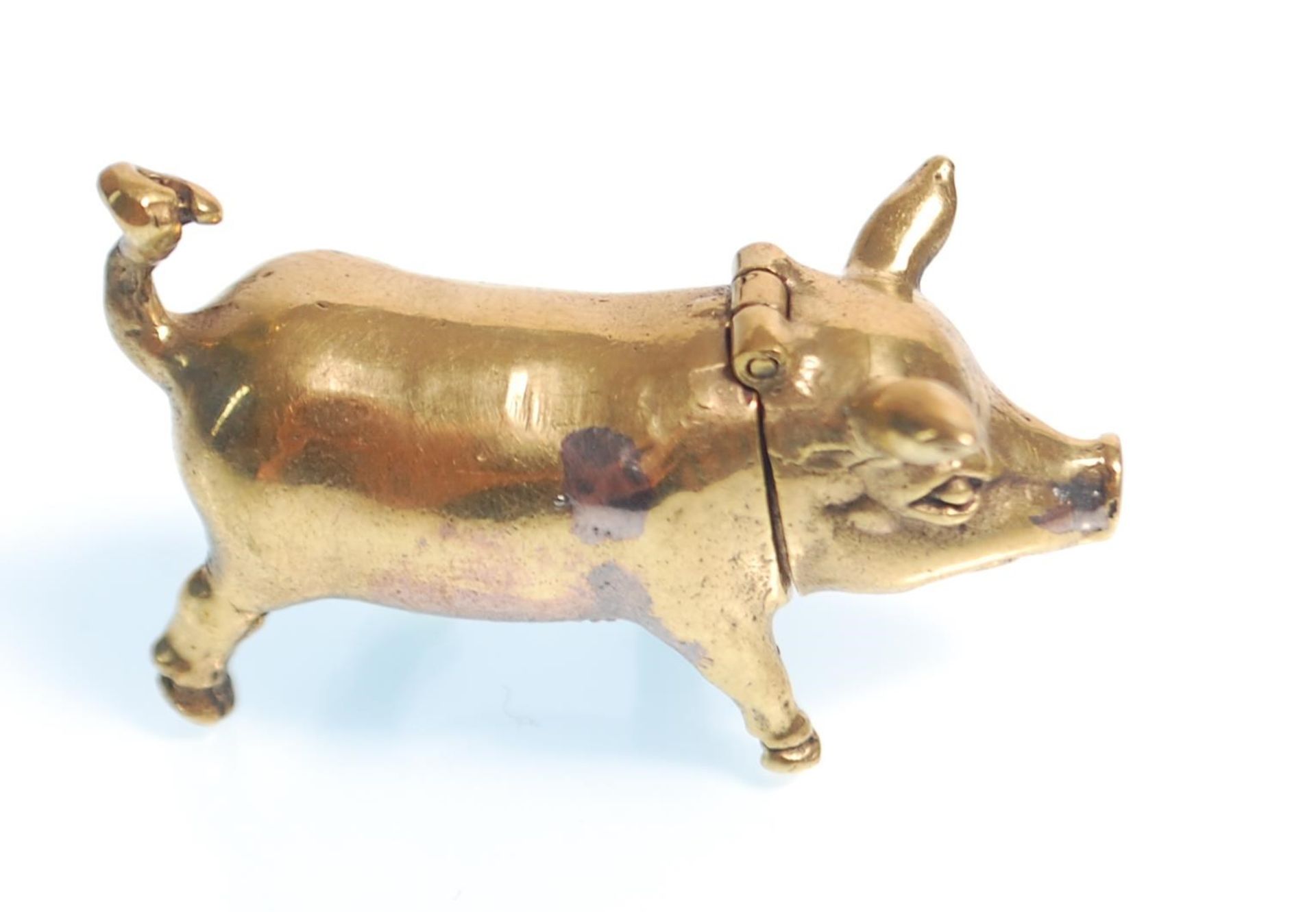 A brass vesta in the form of a pig being hinged at the neck having a match striker to the belly.