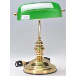 A vintage style bankers desk lamp having an adjustable brass support raised on a stepped brass base.