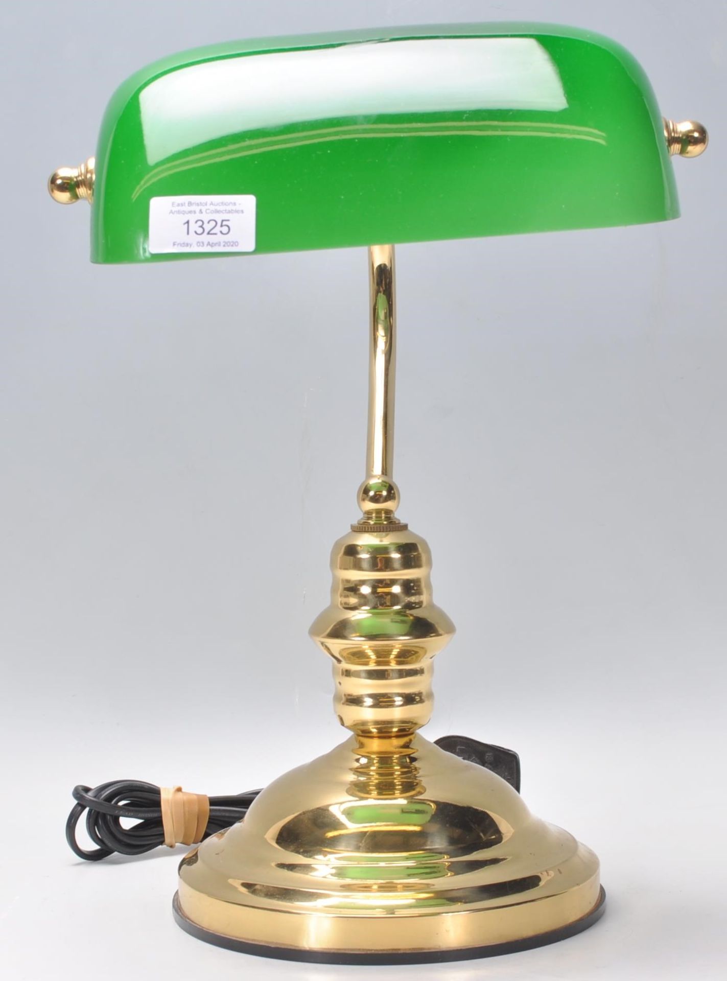 A vintage style bankers desk lamp having an adjustable brass support raised on a stepped brass base.