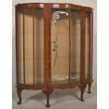 A mid 20th Century walnut china / bookcase display cabinet having a bowed serpentine front with