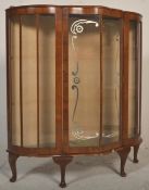 A mid 20th Century walnut china / bookcase display cabinet having a bowed serpentine front with