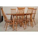 Ercol - A vintage 20th Century blonde beech and elm wood refectory plank dining table being raised