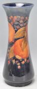 A good William Moorcroft pomegranate pattern vase having a dark blue ground with flared rim atop.