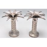 A pair of silver plated candlesticks in the from of palm trees raised on round bases with textured