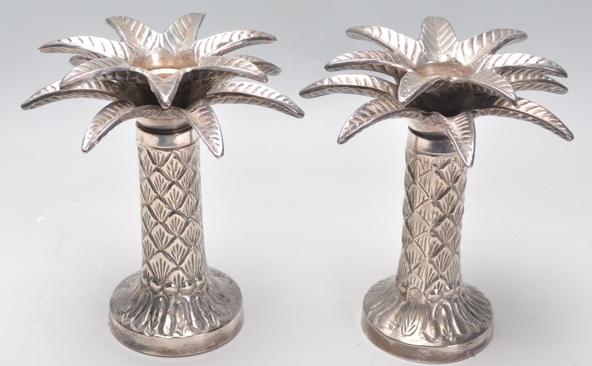 A pair of silver plated candlesticks in the from of palm trees raised on round bases with textured