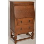 A 1920s Art Deco oak bureau decorated with a floral pediment top set over a fall front writing
