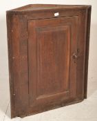 A George III 19th century country oak hanging corner cabinet. Full length fielded panel door with