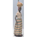 A Nao large figurine in the form of an African lady balancing a basket of fruit on her head,