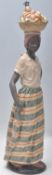 A Nao large figurine in the form of an African lady balancing a basket of fruit on her head,