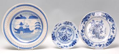 A group of three blue and white delft plates to include an 18th Century plate decorated with a