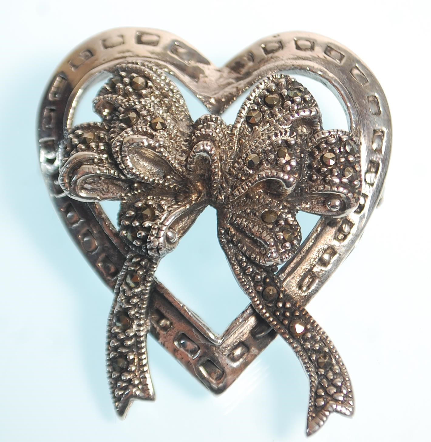 A stamped 925 silver heart brooch with bow decoration to the centre set with marcasites. Measures