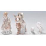 A group of four Lladro figurines a lady with a ginger cat, a boy hugging a donkey and two duck