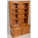 Ercol - A retro style beech and elm sideboard display cabinet comprising of a glazed twin door