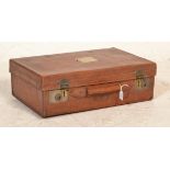 A good quality early 20th century leather suitcase with clasp locks and leather handles, remains