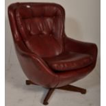 A retro mid century swivel egg chair  having a 4 point swivel base with faux burgundy leather swivel