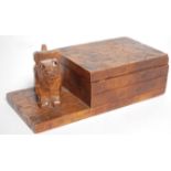 An early 20th Century Folk Art carved wooden cigarette box of rectangular form raised on a plinth