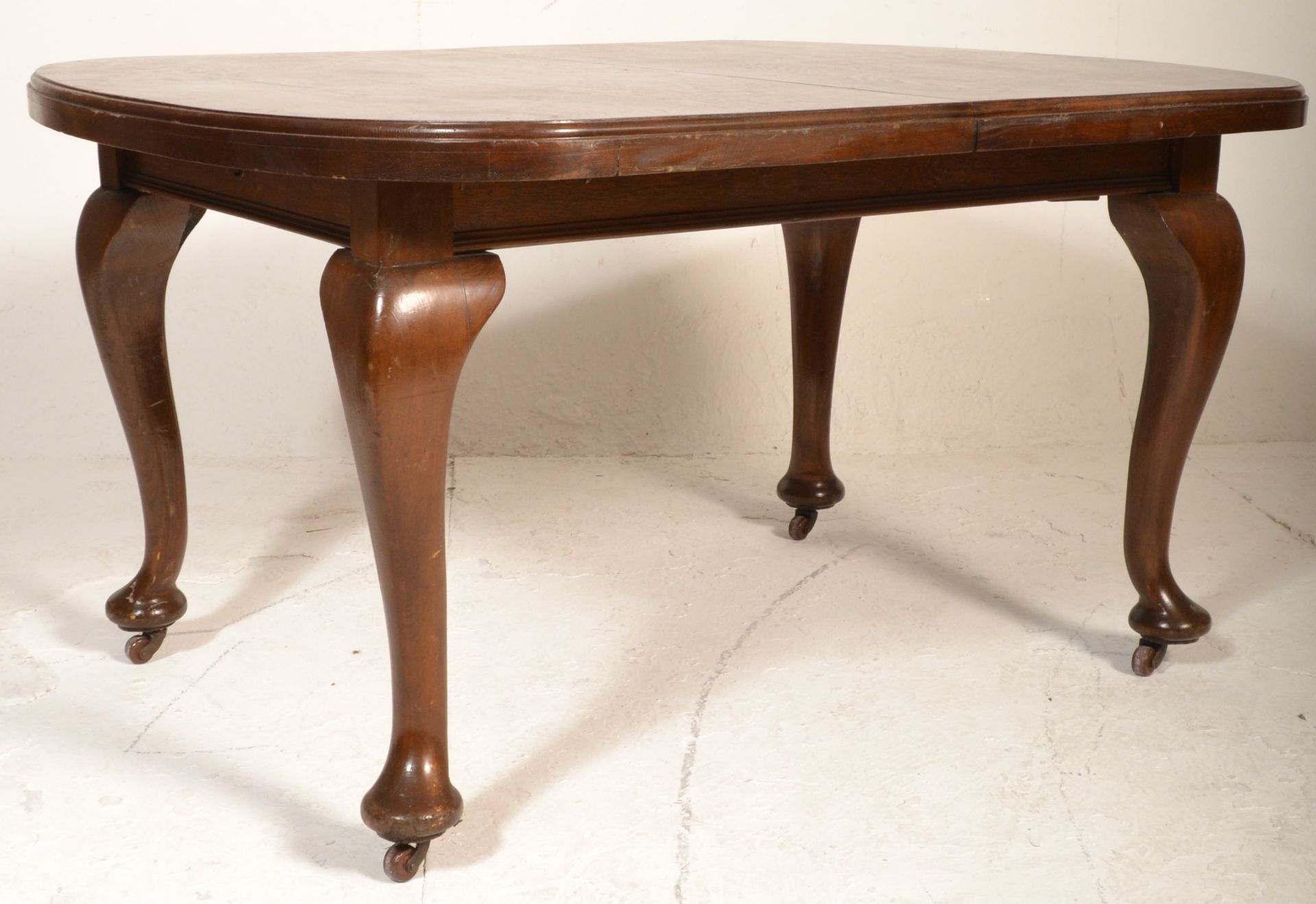 An Edwardian solid mahogany extending dining table being raised on cabriole legs with pad feet