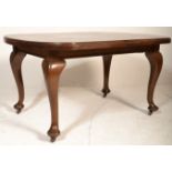 An Edwardian solid mahogany extending dining table being raised on cabriole legs with pad feet