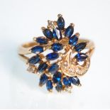 A decorative 14ct yellow gold ladies ring set with sapphires and diamond chips to a peacock style