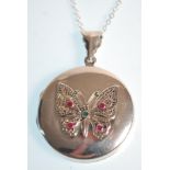 A stamped 925 silver pendant necklace having a round locket with butterfly decoration set with red