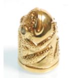 A gold plated thimble in the form of a frog having green stone eyes. Measures 2.5cm tall.