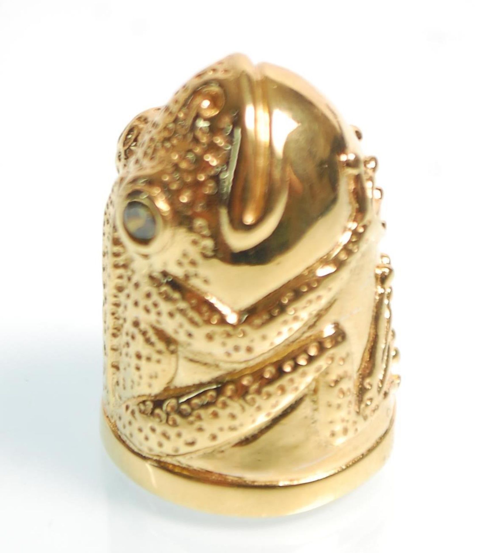 A gold plated thimble in the form of a frog having green stone eyes. Measures 2.5cm tall.