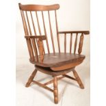 An early 20th century spindle back swivel Windsor arm chair having shaped arm supports and raised on