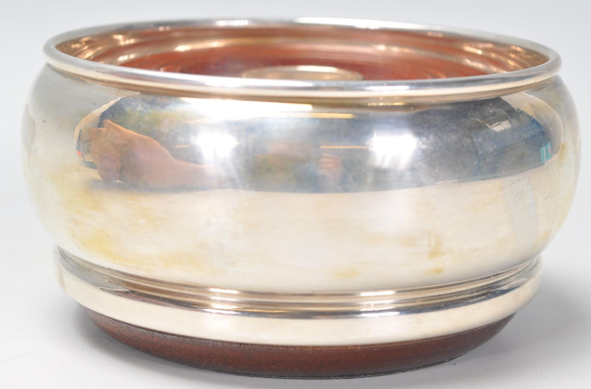 A good silver hallmarked wine coaster having a round bulbous body raised on a wooden base.