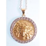 An 18ct gold pendant of round form having a round coin / panel embossed with a medusa head within