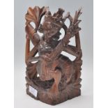 A 20th Century carved dark wood figurine of a Hindu deity Saraswati modelled seated and playing a