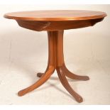A vintage retro teak wood dining table having a round extending table top raised on four central