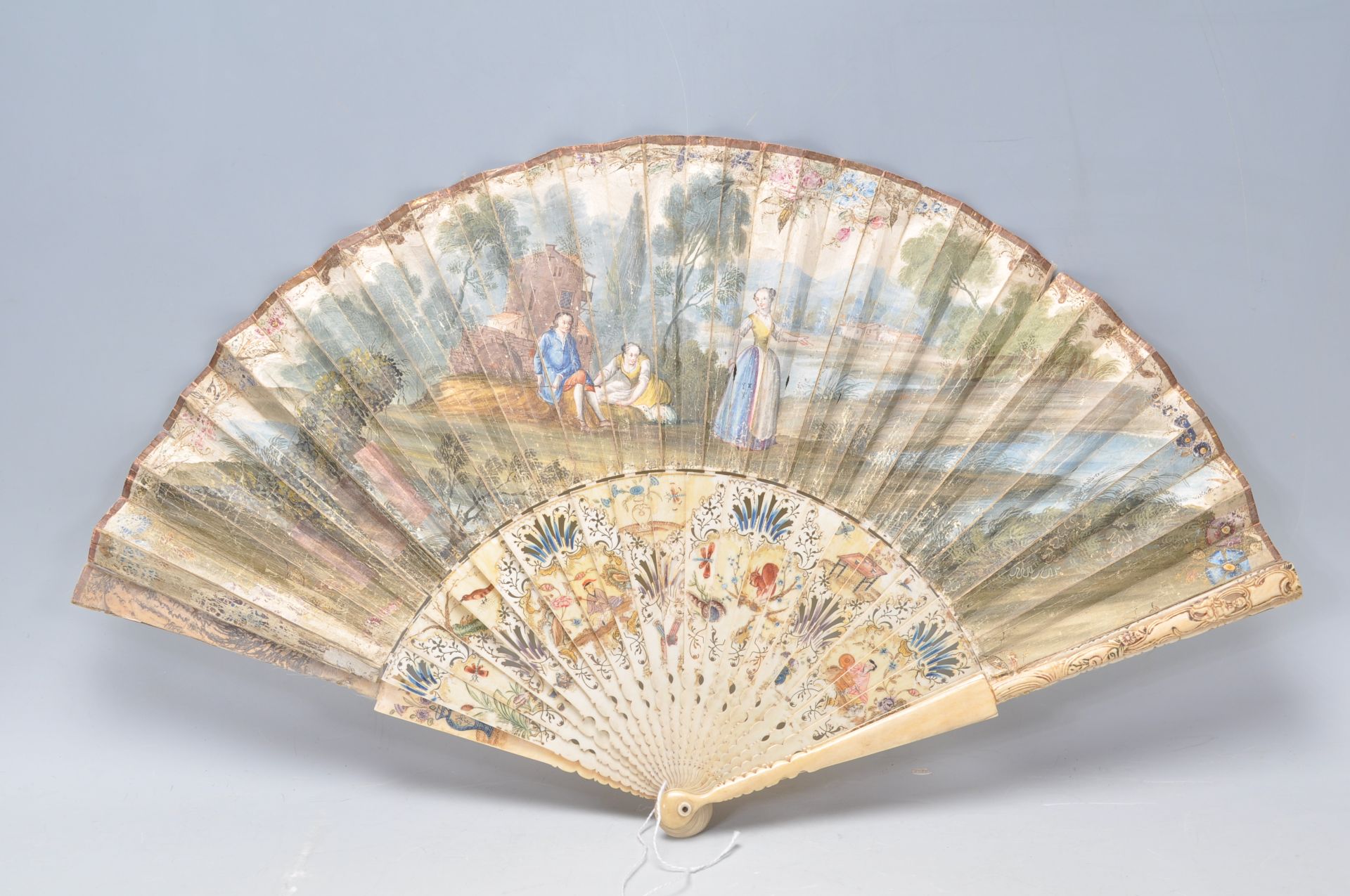 A 19th Century Victorian ivory and paper fan having a hand painted classical river scene to the