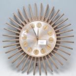 A retro mid 20th century starburst wall clock with circular dial and sunburst surround frame with