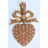 A 19th Century Victorian gold pendant in the form of a heart with a ribbon atop, set with seed