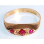 A hallmarked 18ct yellow gold gypsy ring set with three round faceted cut red stones with white