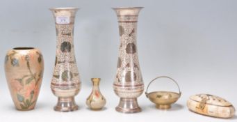 A pair of Indian white metal vases raised on round footed bases with flared rims having engraved