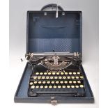 A vintage 20th Century cased Corona folding portable reporters typewriter having a lift up lid