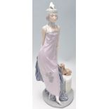 A Lladro figurine depicting a 1920's flapper girl with a feather headdress and puppy. Marked
