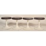 A group of four vintage retro low stools having round leather upholstered seats raised on column