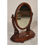 A Victorian 19th century mahogany toilet swing mirror being raised on a shaped base with scrolled