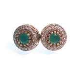 A pair of stamped 925 silver stud earrings of round form being set with round cut green stones and