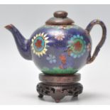 A 19th Century Chinese miniature cloisonne teapot with floral and geometric patterns on a dark