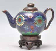 A 19th Century Chinese miniature cloisonne teapot with floral and geometric patterns on a dark
