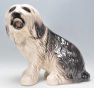 A 20th Century large glazed ceramic figure in the form of an Old English Sheepdog in a seated