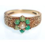 A hallmarked 9ct gold ring having bark effect shoulders with a flower head seat with green stone