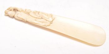 A 19th Century Chinese ivory shoe horn having a handle carved with a figure of a woman and child