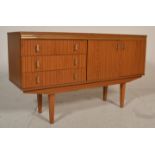 A retro mid 20th Century melamine sideboard credenza raised on tapering teak supports, having a bank