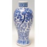 A 19th Century Chinese porcelain blue and white baluster vase being hand painted with scrolling