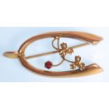 A 19th Century Victorian brooch stamped 9ct gold moulded as a wishbone set with a red faceted cut